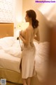 A woman in a white dress standing on a bed.