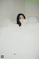 A woman is sitting in a bathtub filled with foam.