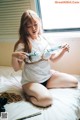 A woman sitting on a bed holding a pair of scissors.