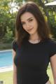 A woman in a black shirt posing by a pool.