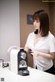 A woman in a white shirt is using a water dispenser.