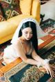 A woman in a wedding dress sitting on a rug.