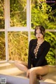 A woman sitting on a window sill in a black bodysuit.