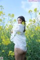 A woman standing in a field of yellow flowers.