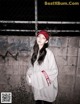 A woman standing in front of a wall wearing a red hat.