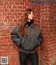 A woman standing in front of a brick wall.