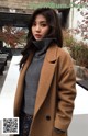 a woman in a brown coat standing in front of a building