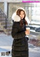 A woman in a black coat holding a cup of coffee.