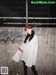 A woman standing in front of a wall wearing a baseball cap.