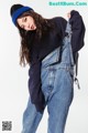 A woman in overalls and a sweatshirt is posing for a picture.