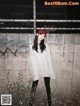 A woman standing in front of a wall wearing a red hat.