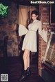 A woman in a white dress standing next to a jukebox.