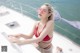 A woman in a red bikini sitting on a boat.