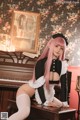 A woman with pink hair sitting on a piano.