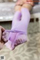 A woman in a pink bikini is tied up with purple gloves.