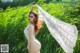 A woman in a white dress standing in a field of tall grass.