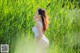 A woman in a white bodysuit standing in tall grass.