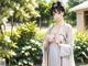 A woman in a white kimono standing in a garden.