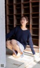 A woman sitting on the ground in front of a wooden cabinet.