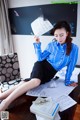 A woman sitting at a desk holding a piece of paper.