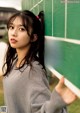 A young woman leaning against a green wall with the word out written on it.