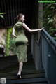 A woman in a green dress standing on a set of stairs.