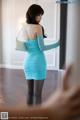 A woman in a blue dress standing in front of a mirror.