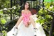 A woman in a pink dress sitting on a white rug.