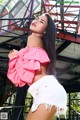 A woman in a pink top and white shorts posing for a picture.