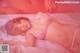 A woman laying on a bed in a pink lingerie.