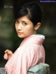 A woman in a pink kimono is posing for a picture.