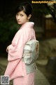 A woman in a pink kimono is posing for a picture.