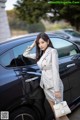 A woman standing next to a black car with a handbag.