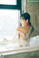 A woman in a bathtub with foam on her back.