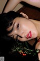 A woman laying on a table with a bunch of berries in her hand.