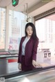 A woman in a business suit standing in front of a window.