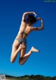 A woman in a bikini jumping in the air.