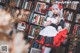 A woman dressed in a maid outfit standing in front of a bookshelf.