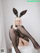 A woman in a bunny costume sitting on a white stool.