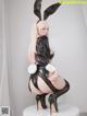 A woman in a bunny costume is posing on a white pedestal.