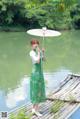 A woman in a green dress holding an umbrella.