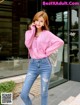 A woman in a pink shirt and jeans posing for a picture.