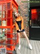 A woman standing in front of a red phone booth.