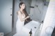 A woman standing in front of a sink in a bathroom.