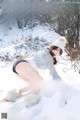 A woman in a white hat is posing in the snow.