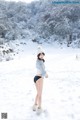 A woman standing in the snow wearing a hat and boots.