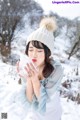 A woman in a white hat blowing snow in the air.