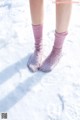 A person standing in the snow wearing pink socks.