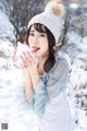 A woman in a white hat is blowing snow in the air.