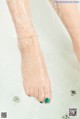 A woman's feet in a bathtub with water splashing on them.